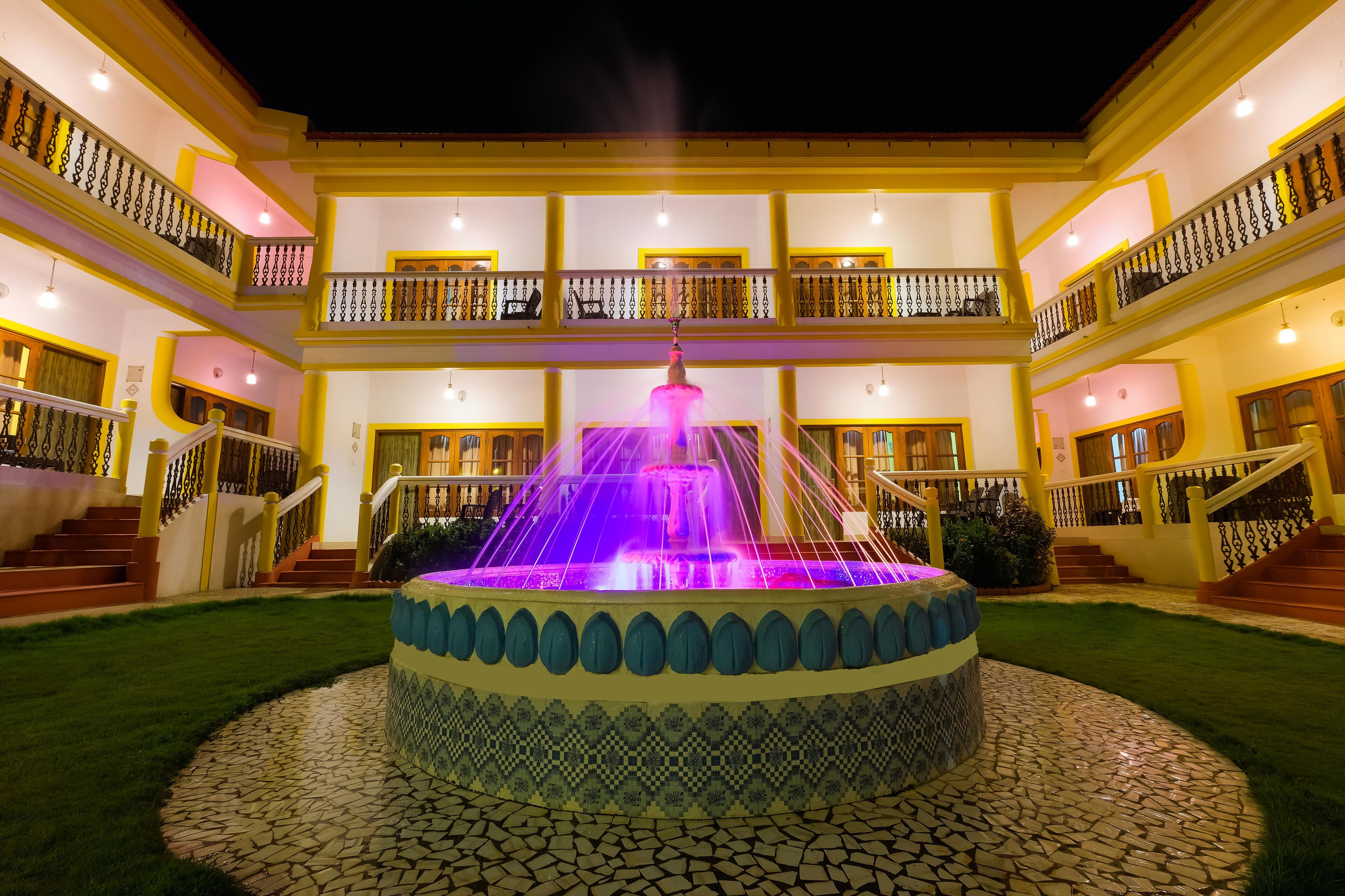A multi-story building with a central fountain, balconies, and a tiled courtyard.