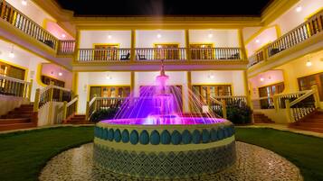 A multi-story building with a central fountain, balconies, and a tiled courtyard.