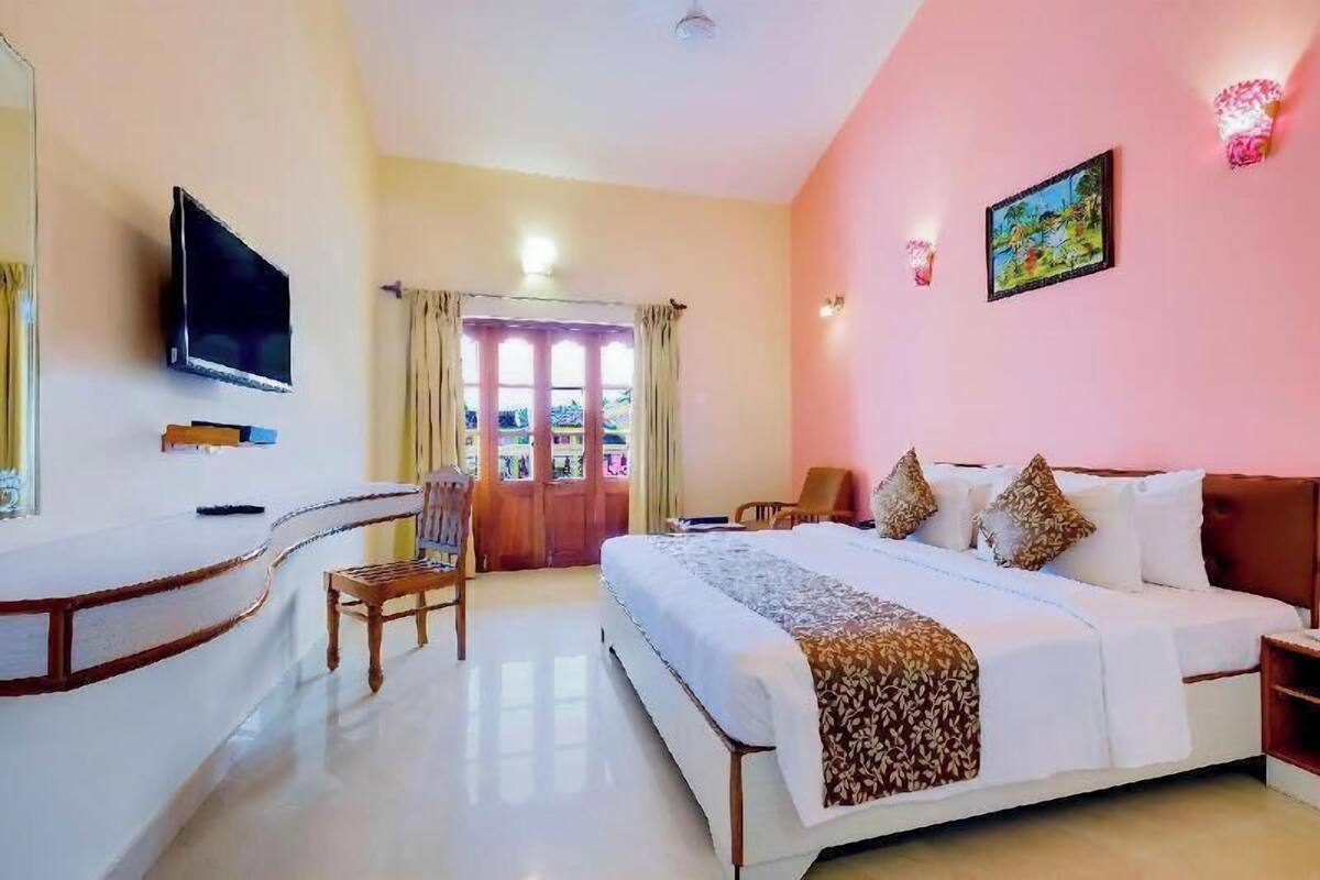 Une chambre d’hôtel avec un lit, une télévision, un bureau et une chaise.