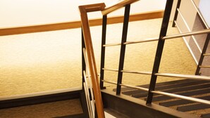 Una escalera de madera con barandillas metálicas y peldaños alfombrados.