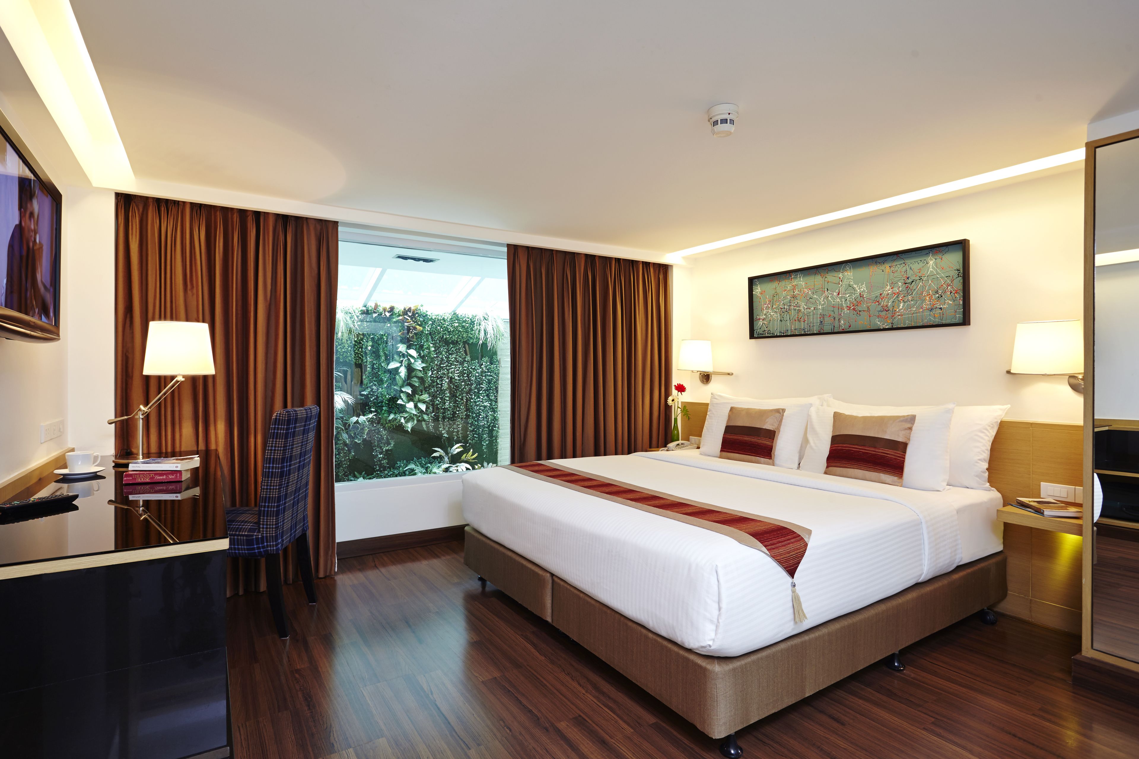 A hotel room with a large bed, a desk, a chair, and a window with curtains.