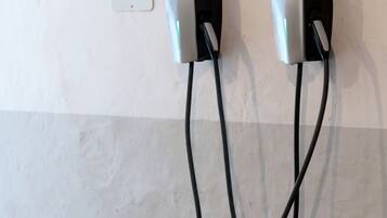 A wall-mounted electric vehicle charging station with two charging points and a cable on the floor.