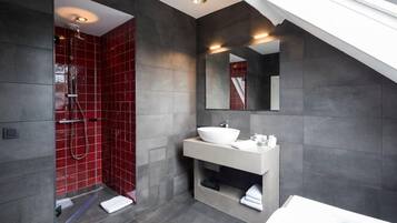 Un baño moderno con ducha a ras de suelo, un espejo grande y una bañera.