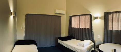 Una camera d'albergo con due letti singoli, un tavolino e una sedia.