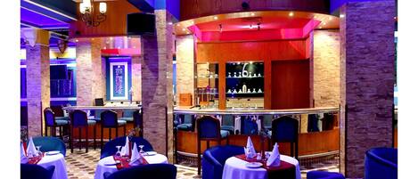 A restaurant with a bar area, multiple tables, and chairs.