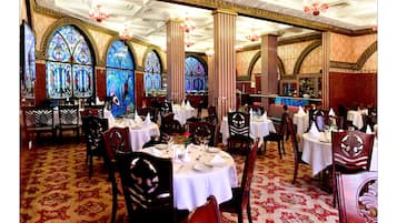 A banquet hall with round tables, chairs, and stained glass windows.
