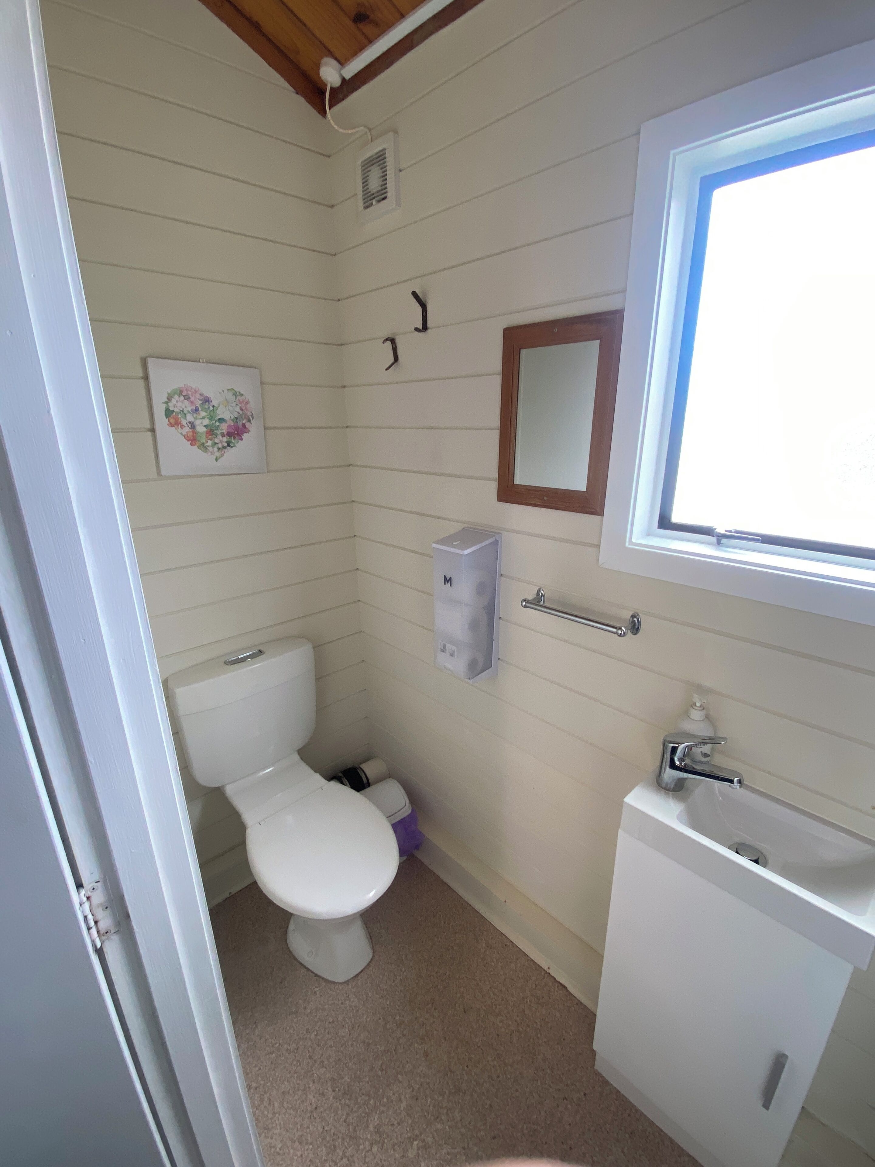 A small, compact bathroom with a toilet, a sink, and a mirror.
