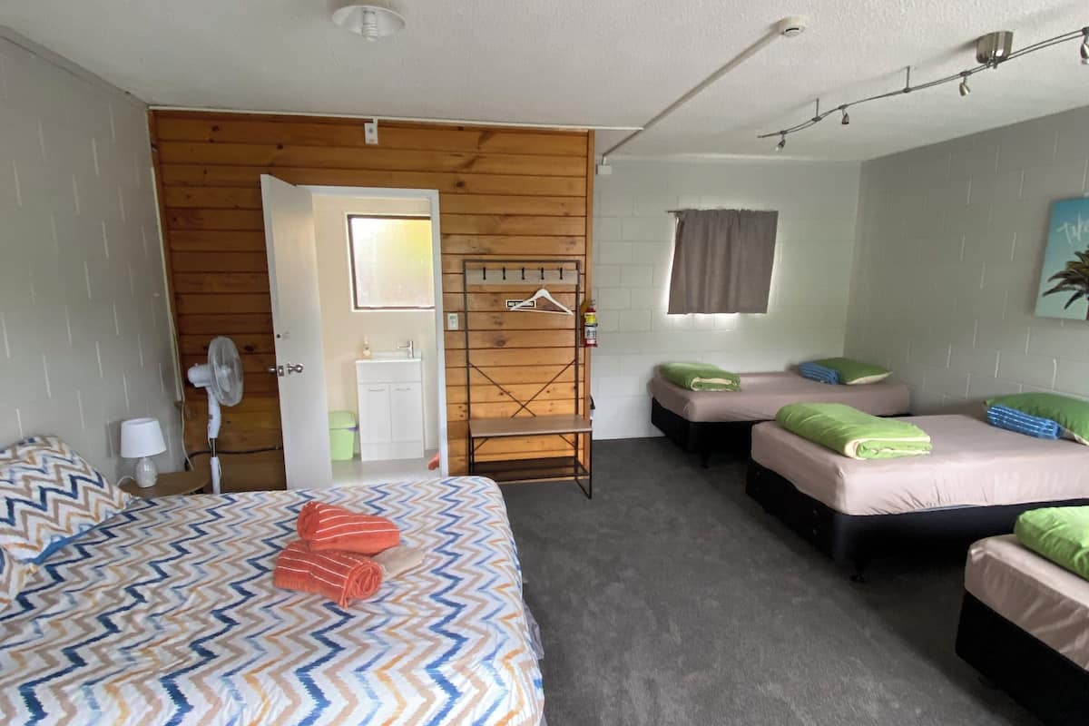 Ein Schlafzimmer mit einem großen Bett, zwei Einzelbetten, einer Holzwand, einem Kleiderschrank und einem Spiegel.