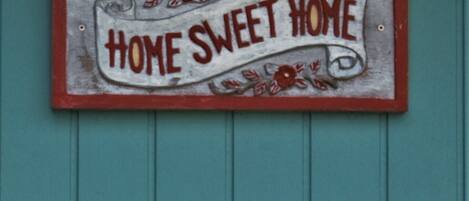 Un cartel con el texto 'HOME SWEET HOME' sobre un fondo verde azulado.