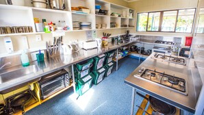 A kitchen with stainless steel appliances, shelves with dishes, and a window providing natural light.
