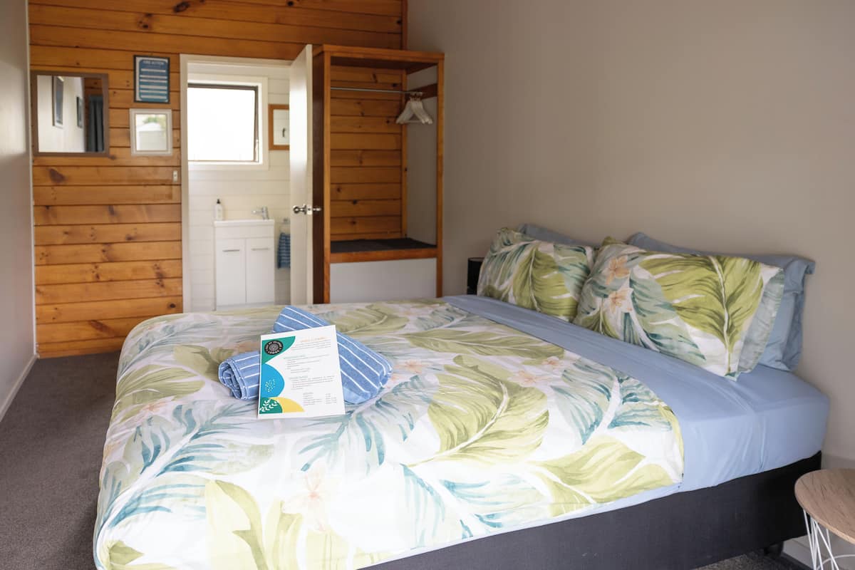Ein Schlafzimmer mit einem Bett, einem Holzschrank, einem Spiegel und einem Fenster.