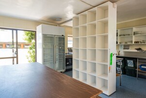 Una cocina con armarios blancos, una mesa de madera y un refrigerador con puerta de vidrio.