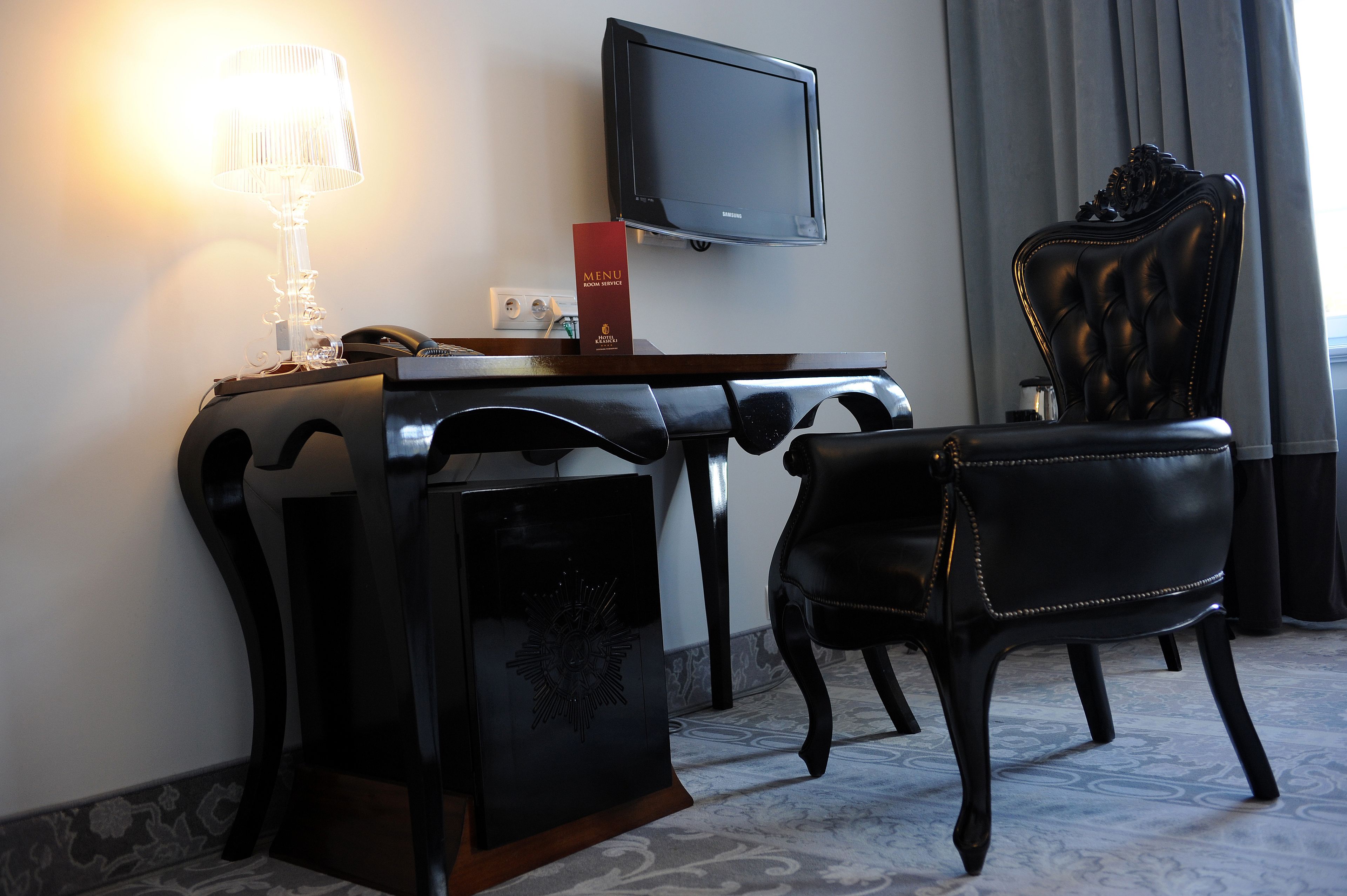 Une chambre d’hôtel équipée d’un bureau, d’une télévision, d’une chaise et d’une lampe.