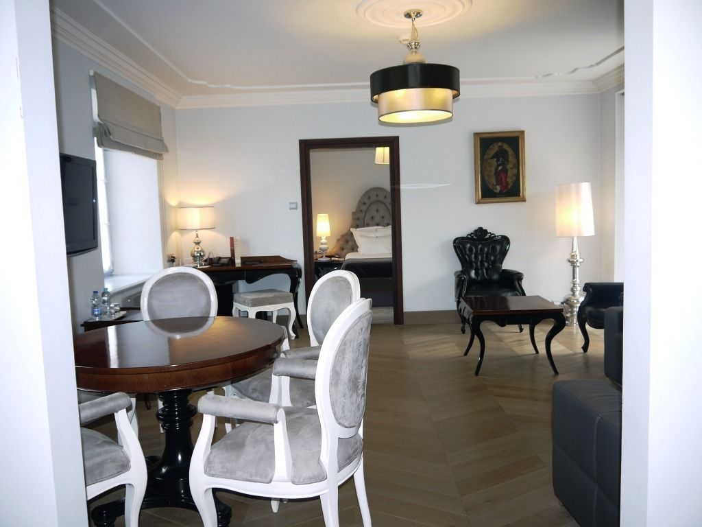 A dining area with a round table and chairs, a sofa, a lamp, and a framed picture on the wall.