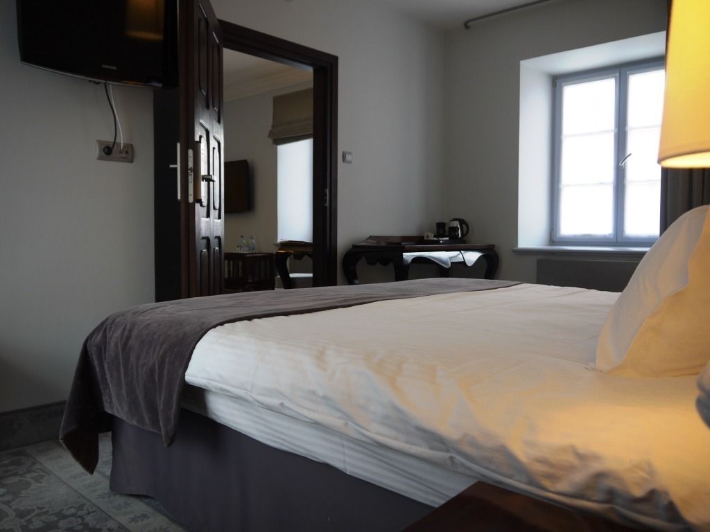Ein Hotelzimmer mit Bett, Schreibtisch, Stuhl, Fernseher und Fenster.