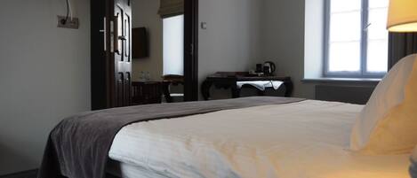 Ein Hotelzimmer mit Bett, Schreibtisch, Stuhl, Fernseher und Fenster.
