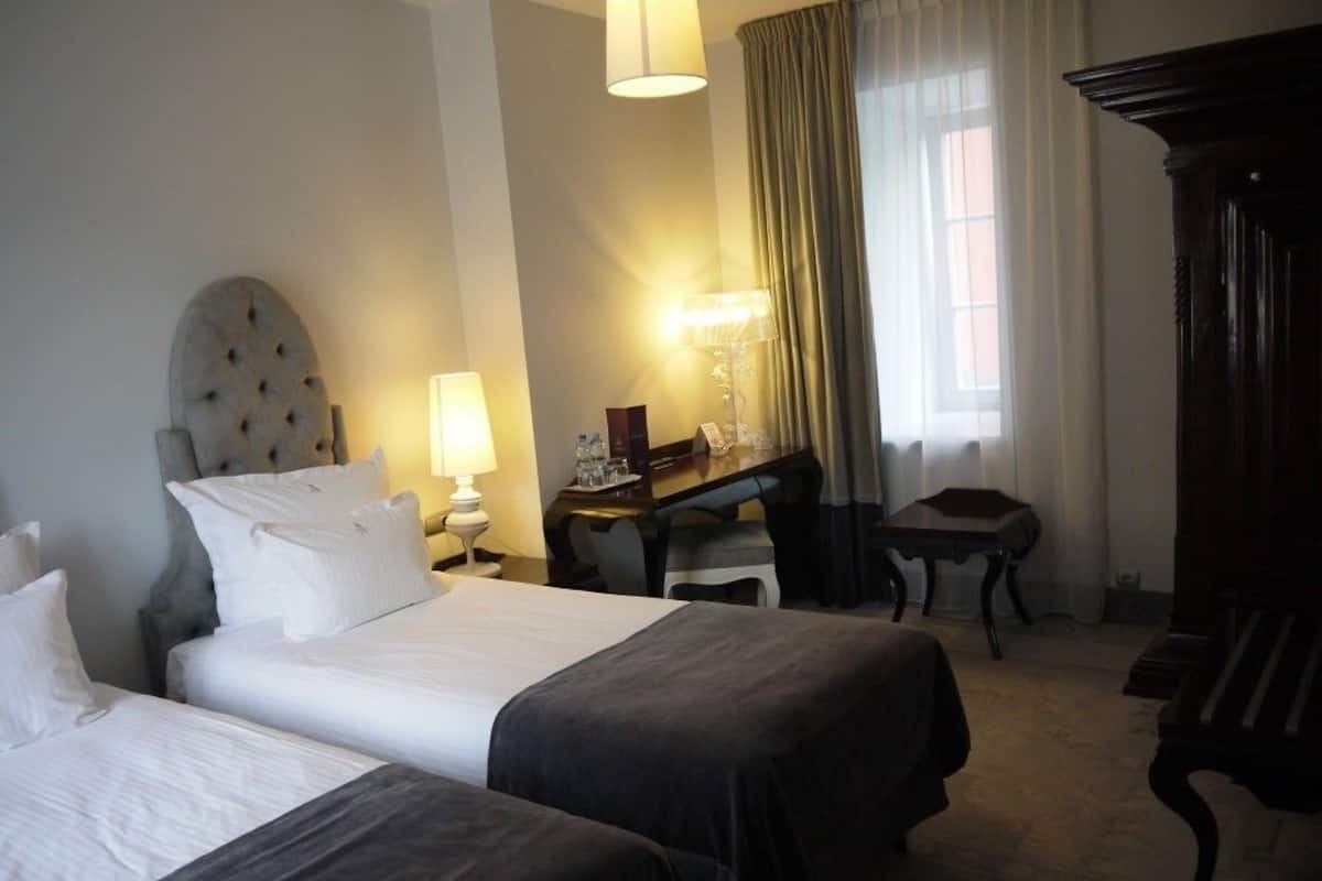 Ett hotellrum med två sängar, ett skrivbord, ett piano och en lampa.
