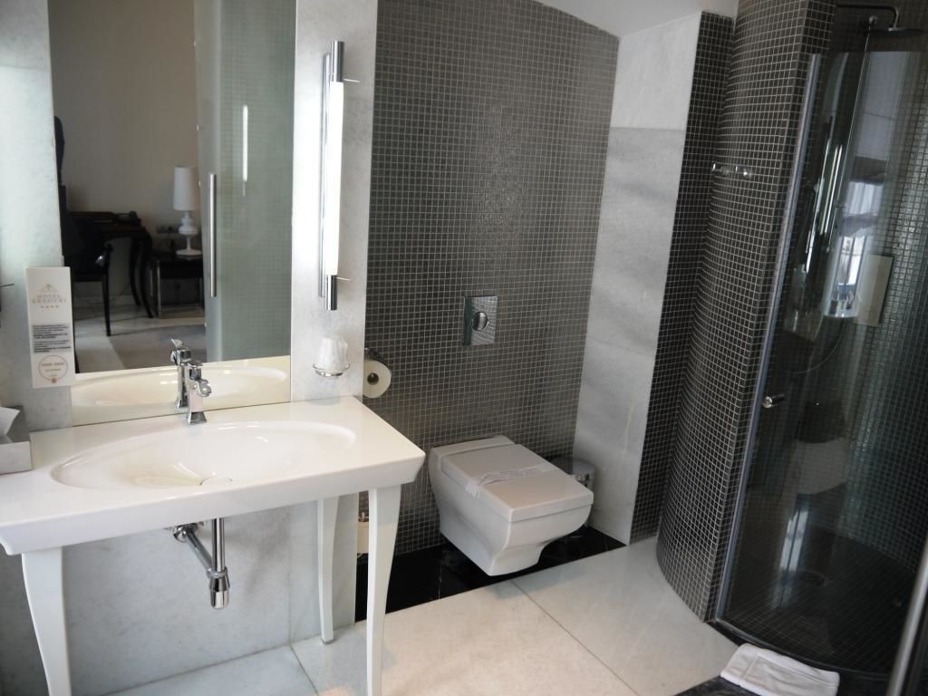 Un baño moderno con un lavabo blanco, un inodoro y una cabina de ducha con paredes de vidrio.