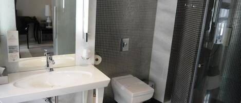 Un baño moderno con un lavabo blanco, un inodoro y una cabina de ducha con paredes de vidrio.