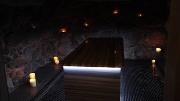 Un espacio de spa con banco de madera, paredes de piedra y velas.