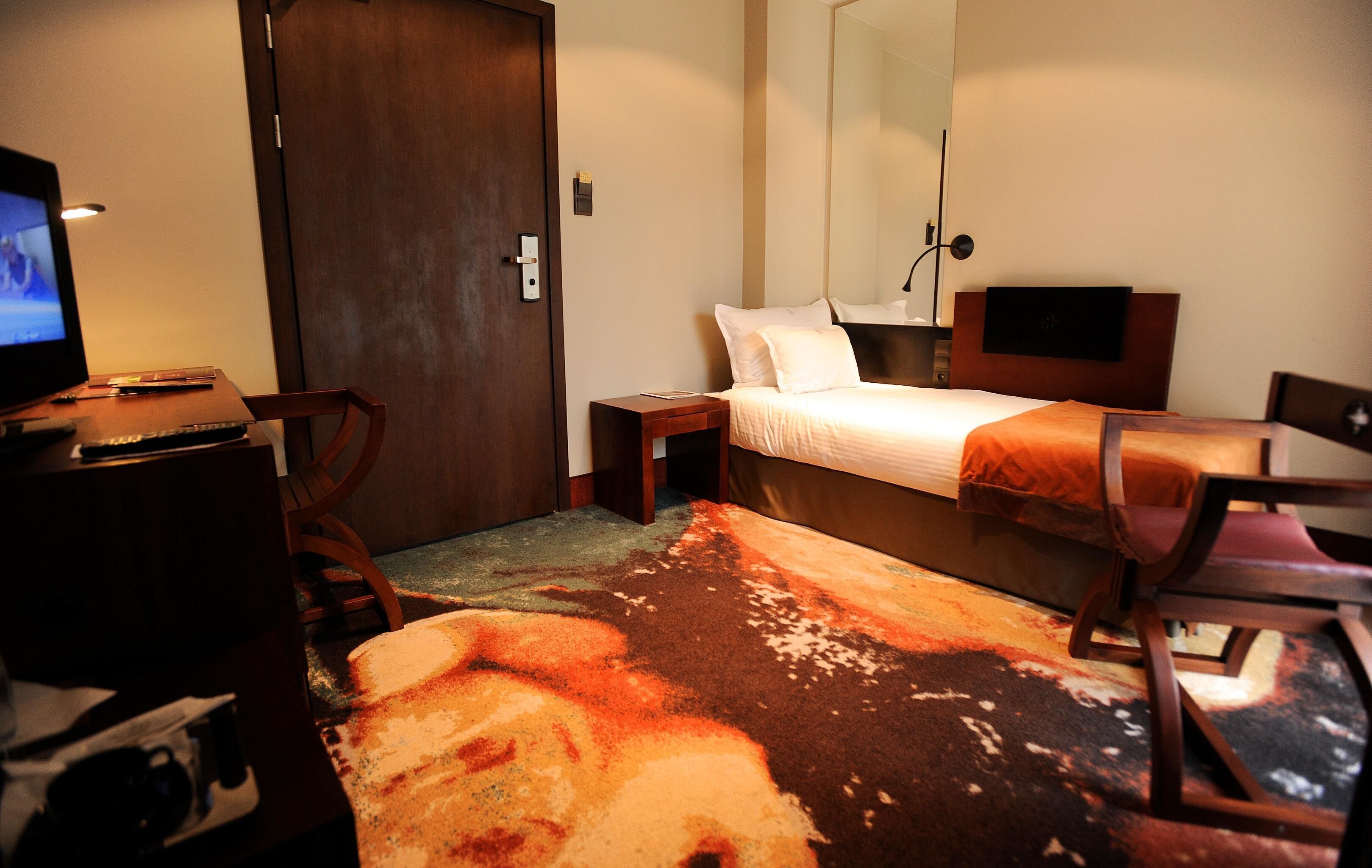 Una camera d'albergo con un letto, una scrivania con un computer, una sedia e una televisione.