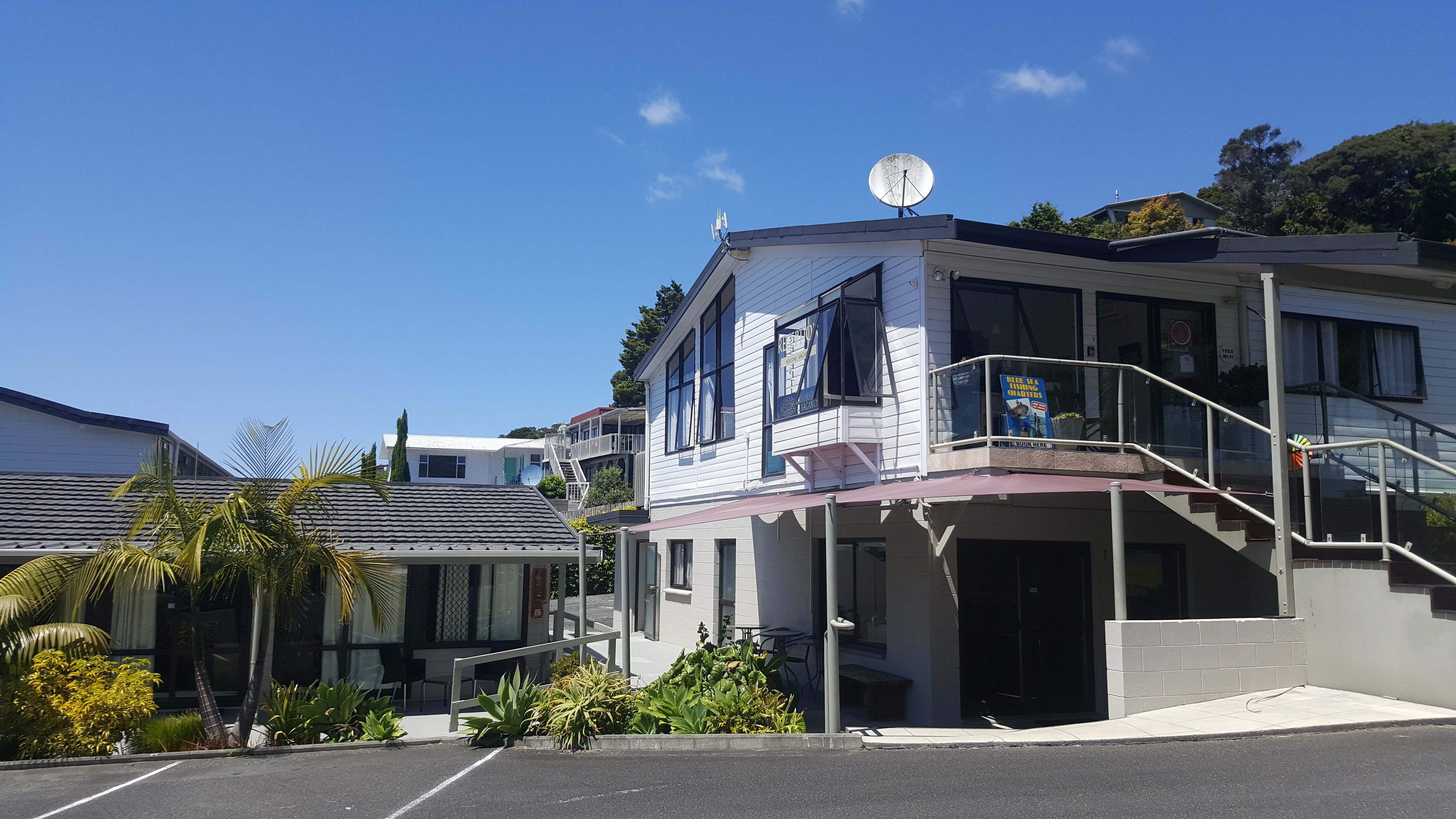A two-story building with a balcony, a satellite dish, and a sign advertising 'Blue Sea Fishing Charters'.