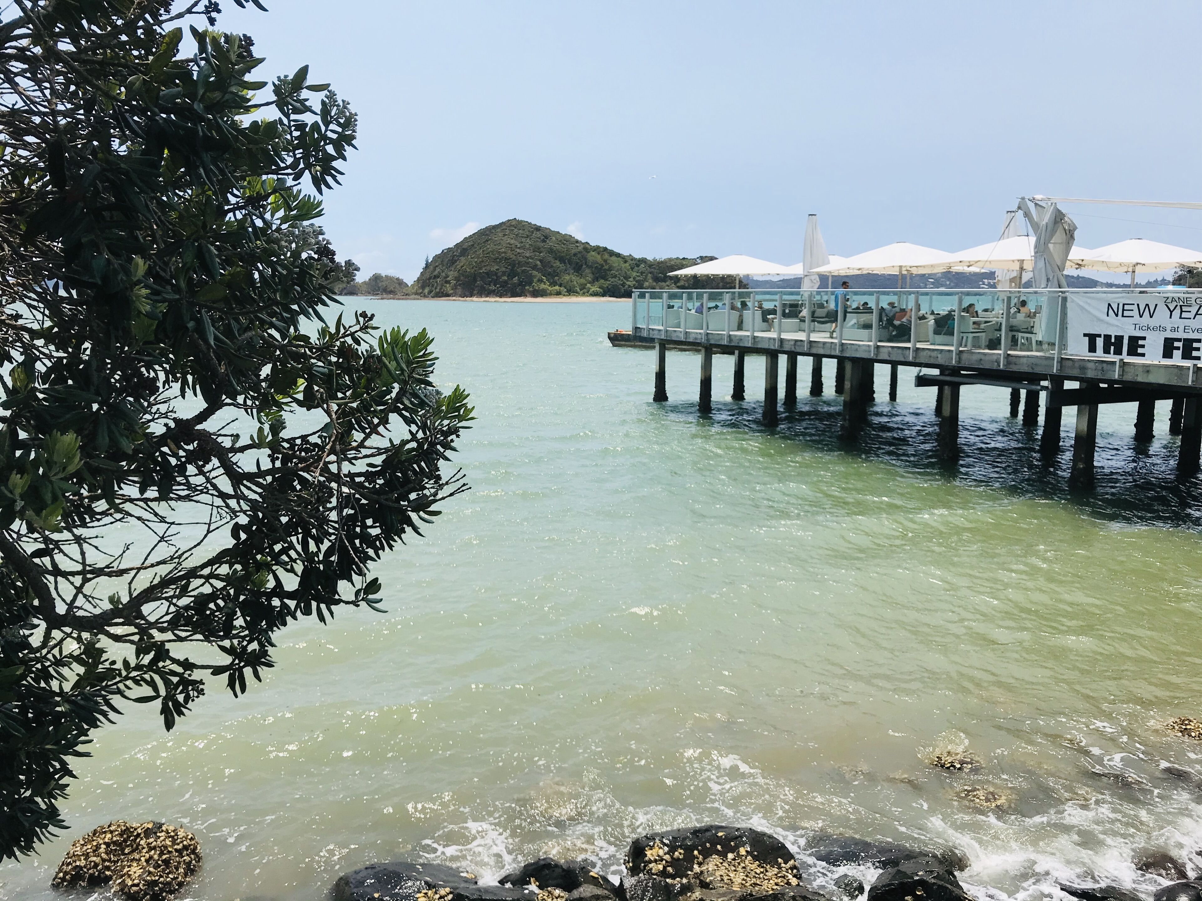Un muelle se adentra en aguas tranquilas, con un restaurante a la derecha.