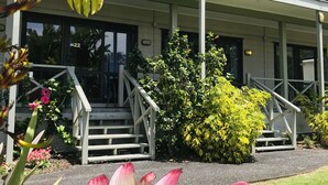 A building with a covered entrance, steps, and a small garden area with various plants. - Bounty Motel (Paihia)
