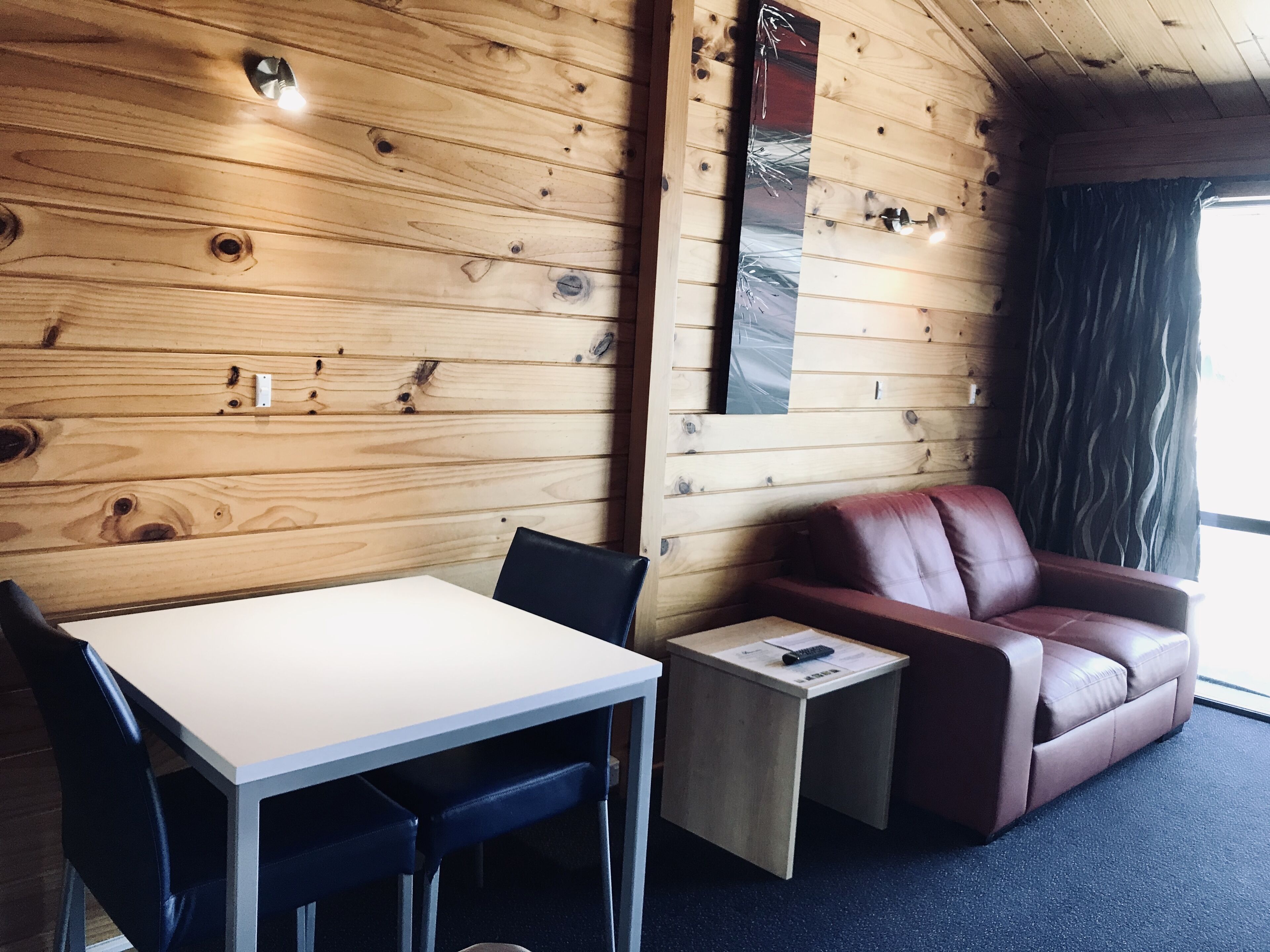 A wooden interior with a table, chairs, a sofa, and a small side table.