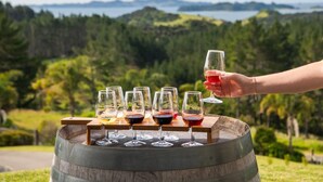 A wooden barrel with wine glasses arranged on top, set against a scenic outdoor backdrop. - Bounty Motel (Paihia)