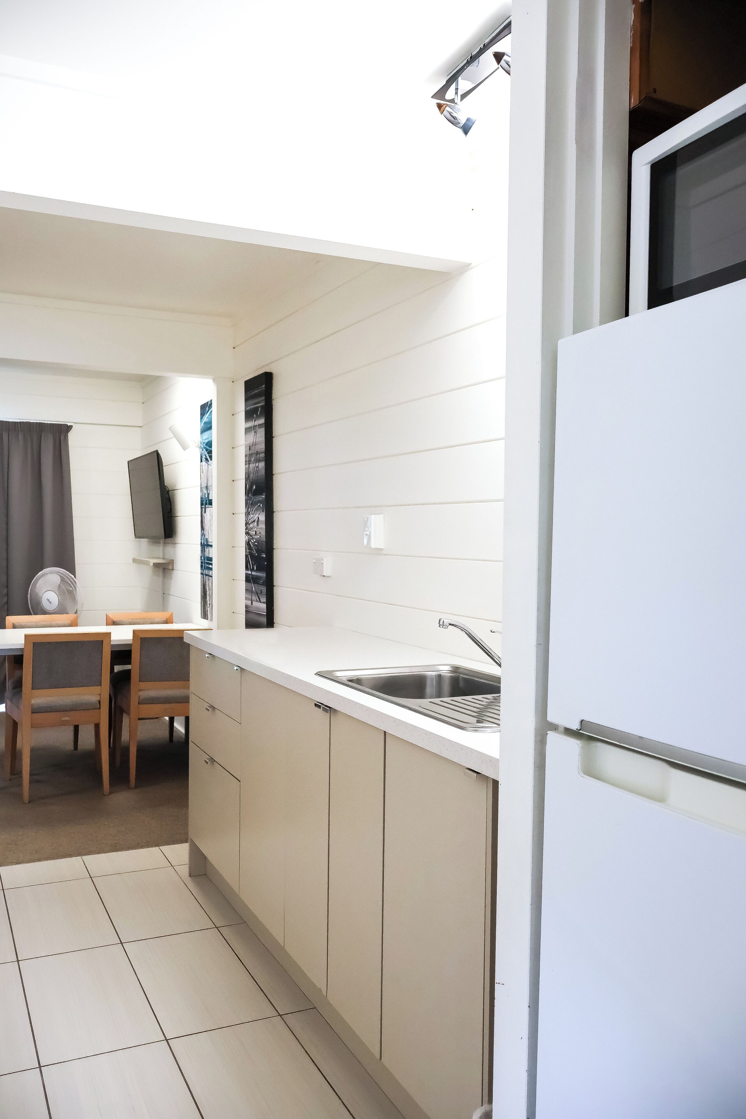 Een kleine keuken met een eethoek, een ingebouwde televisie en een ventilator.