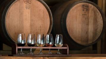 Wine glasses on a rack with wooden barrels in the background.