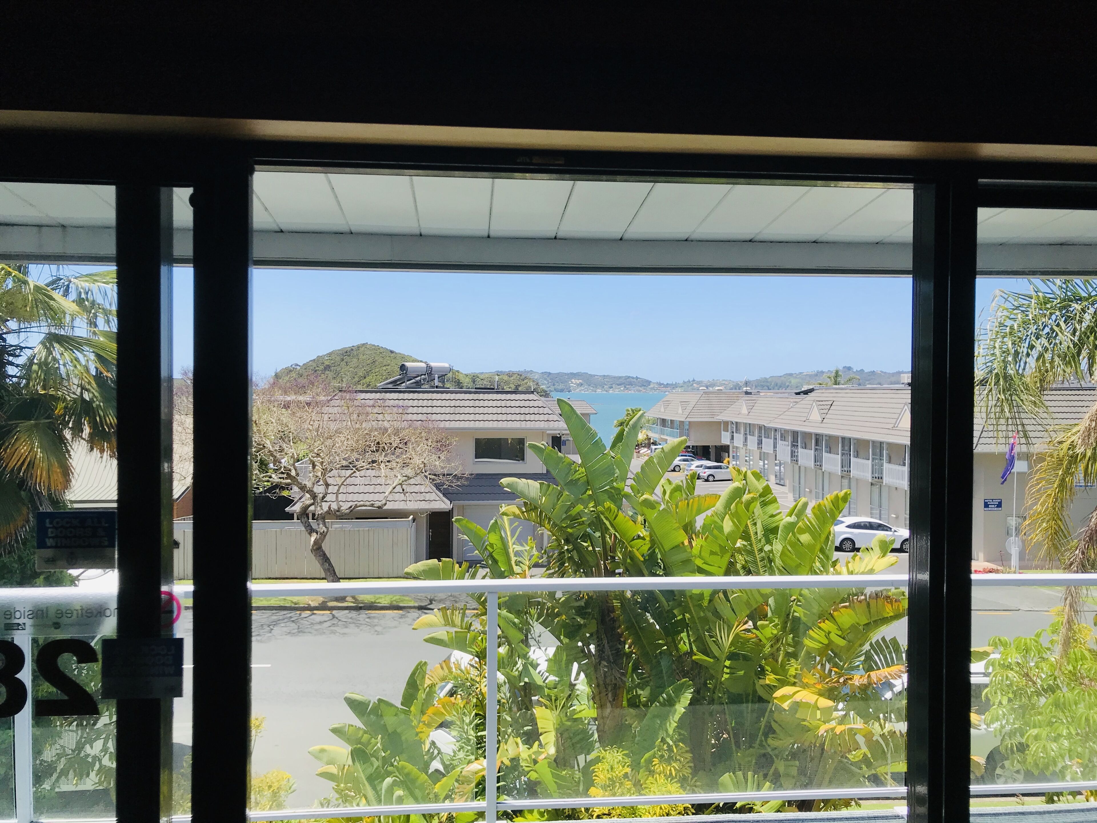 A view from a window overlooking a parking lot with buildings and a hill in the background.