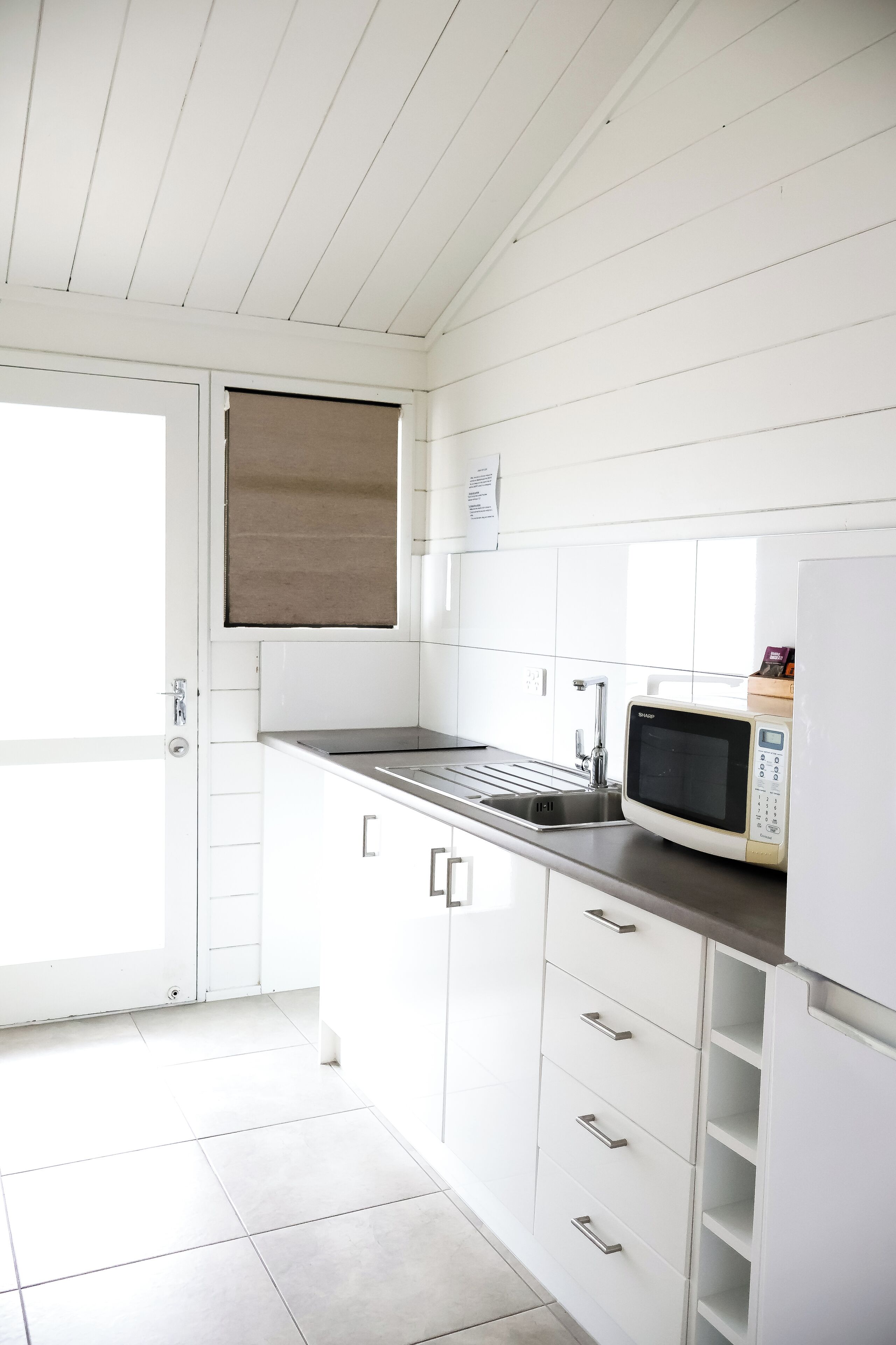 A kitchen with white cabinets, a microwave, and a sink.