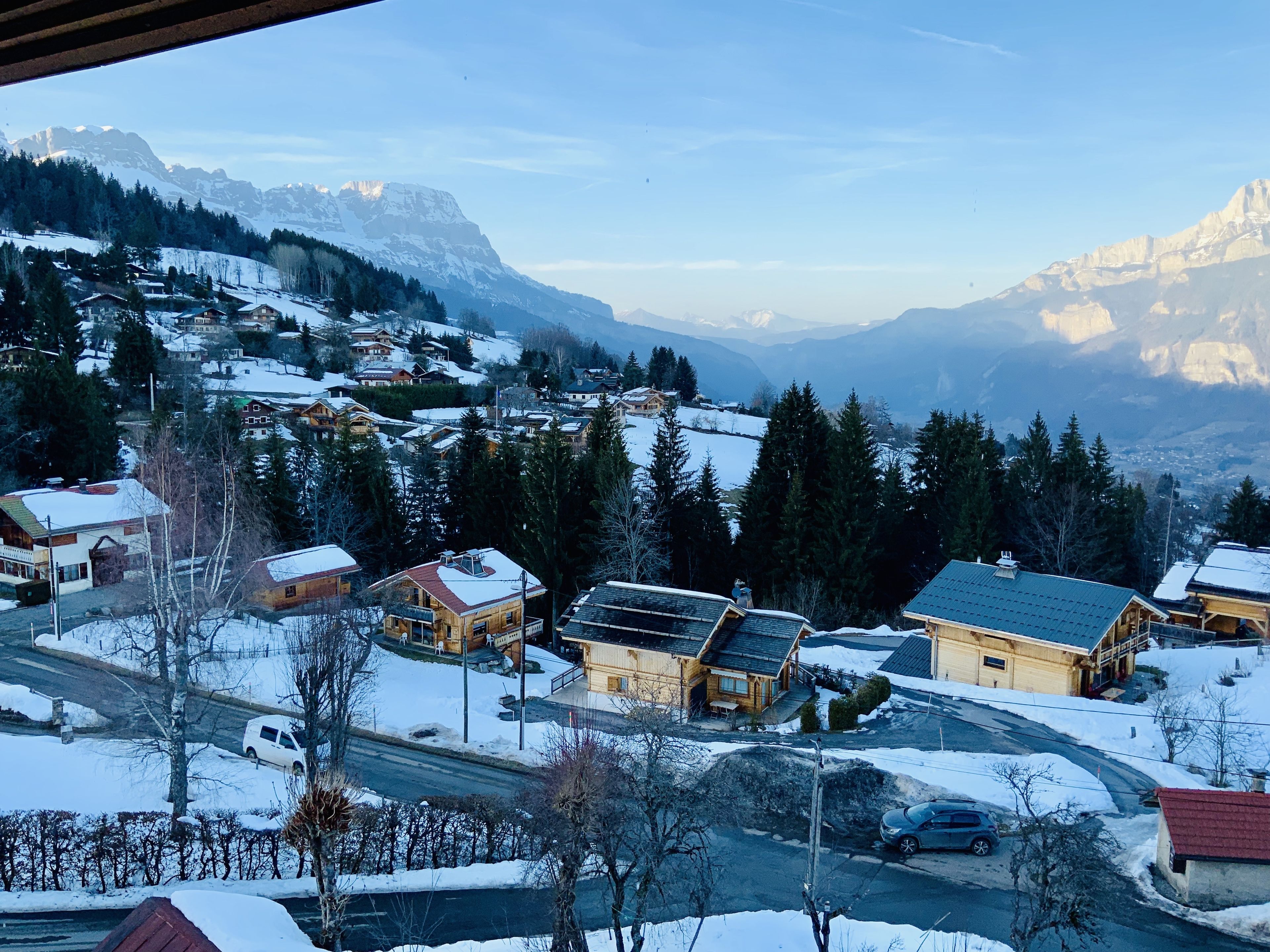 Un pueblo cubierto de nieve con casas de madera y una montaña al fondo.