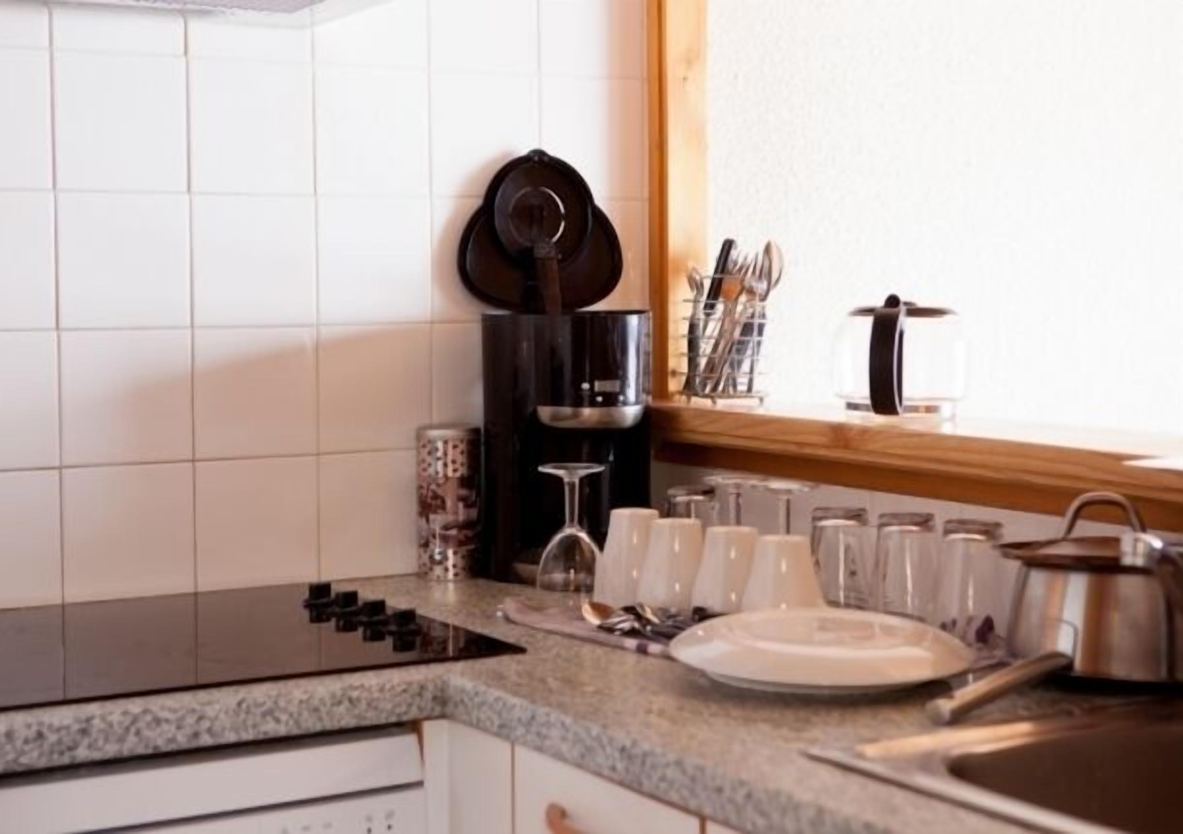 Une cuisine équipée d’une cuisinière, d’une machine à café et d’une fenêtre donnant sur un beau paysage.