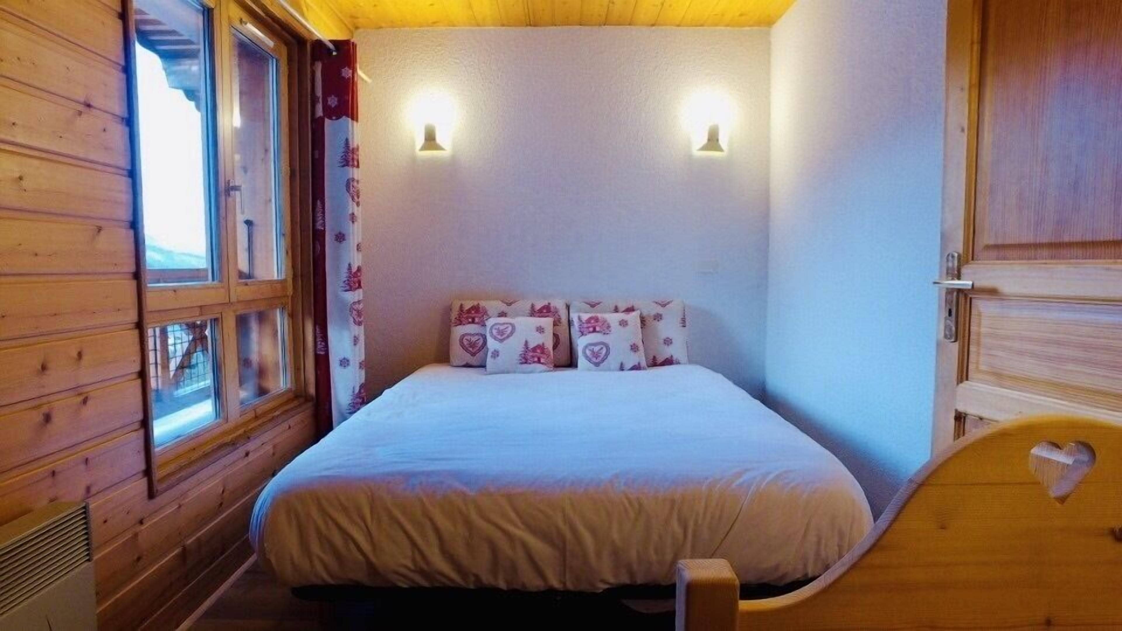 Ein Schlafzimmer einer Holzhütte mit einem Bett, Kissen und zwei Wandleuchten.