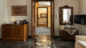 A living room with a wooden cabinet, a glass coffee table with a bottle, glasses, and keys, a television, and a mirror.