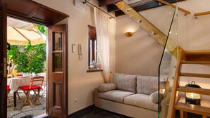 A cozy living room with a sofa, a wooden staircase, and a dining area with a table and chairs.
