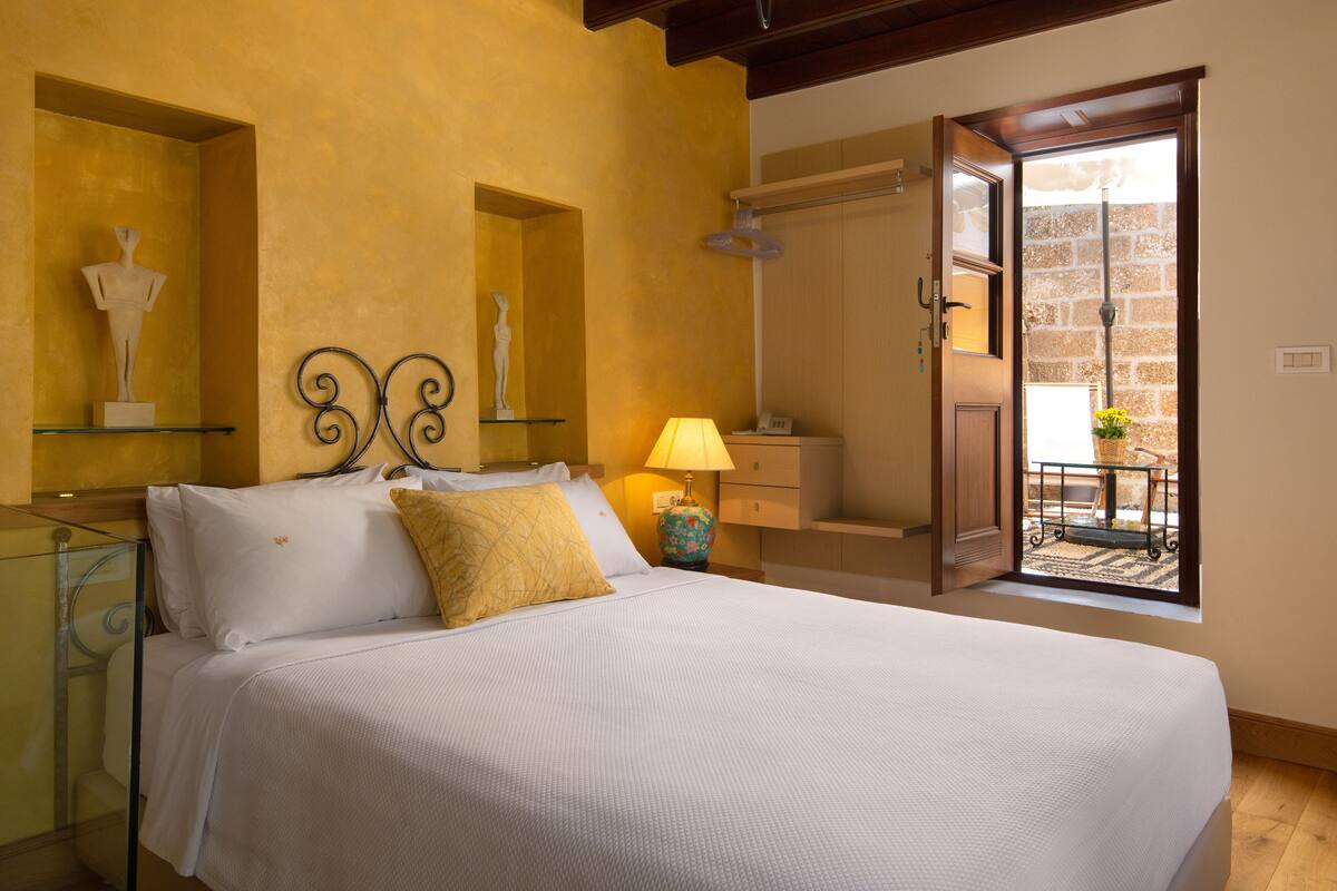 Une chambre à coucher avec un lit, une table de chevet, une lampe et une vue sur un balcon.