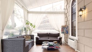 A cozy reading nook with a sofa, a coffee table with books, and a lamp. - Villa Pirandello (Rome)