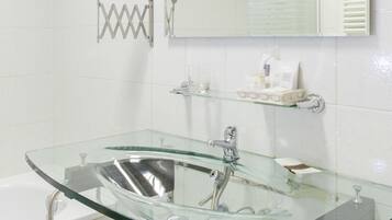 A modern bathroom with a glass sink, a large mirror, and a towel rack.