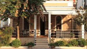 A building with a covered entrance, outdoor seating, and a staircase leading to the entrance. - Villa Pirandello (Rome)