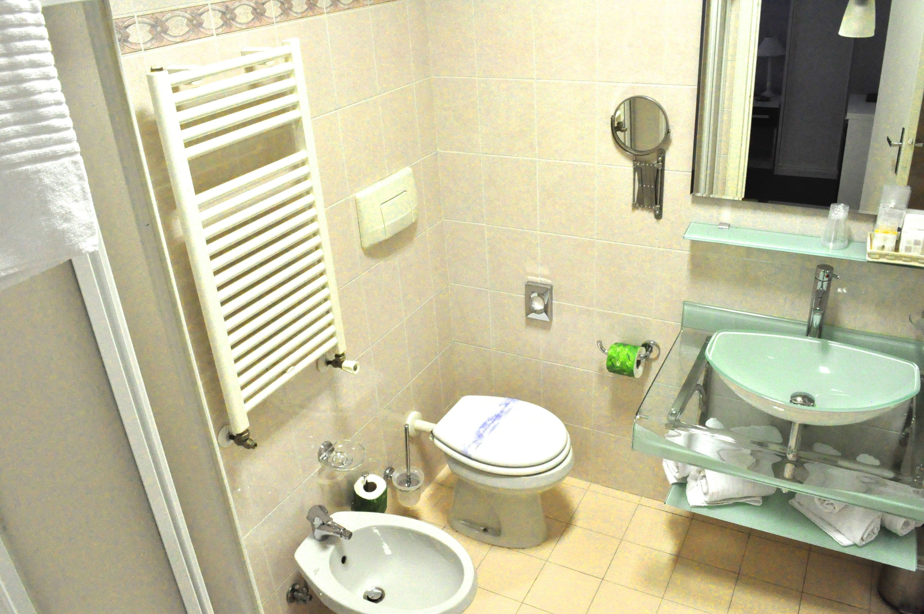 A bathroom with a toilet, sink, towel rack, and a mirror.