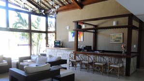 A spacious living area with a sofa, chairs, and a bar area with a computer. - Pousada Praia Bella (Búzios)