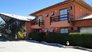 A two-story building with a red facade, multiple windows, and a balcony. - Pousada Praia Bella (B úzios)