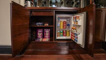 A compact kitchen with a built-in refrigerator stocked with beverages and snacks.