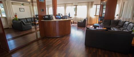 A hotel lobby with a reception desk, seating area, and large windows.