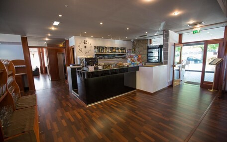 A bar area with a wooden floor, a counter with a glass display, and a wall with a clock.