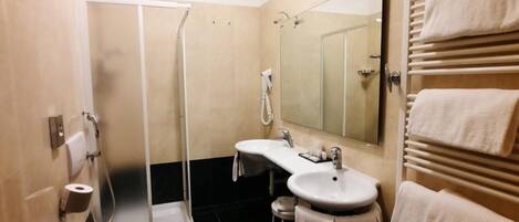 A modern bathroom with a glass shower enclosure, two sinks, a large mirror, and a towel rack.